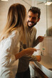 © Novak - A young happy couple brushing their teeth together in the bathroom during their morning routine