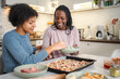 © Jelena - African American mother and daughter making pizza together