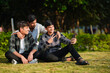 © PRASANNAPIX - three indian college boys using smartphone at garden