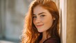 © Anastasiia - Close-up portrait of a smiling red-haired woman with freckles, leaning against a sunlit wall outdoors. Concept Close-up portrait, Red-haired woman, Freckles, Sunlit wall, Outdoor natural light