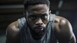 © Anastasiia - Intense close-up of a sweating man wearing a gray sleeveless gym shirt, staring at the camera during a workout. Concept Intense workout close-up, Sweat detail, Focused athlete, Gray sleeveless shirt
