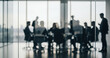 © Wisnu - Business professionals appear as blurred silhouettes behind a glass wall during a formal meeting, expressing focus, strategy, and collaboration inside a bright modern office environment.