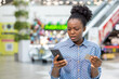 © Liubomir - Shocked young woman in a mall holding credit card and smartphone, reacting to payment failure or possible online banking fraud, worried and frustrated by unexpected charges