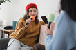 © Studio Marmellata - Two people are recording a podcast together, one holding a microphone and wearing headphones, the other holding a microphone and a phone.