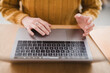 © Studio Marmellata - A person wearing a yellow sweater uses a laptop, their hands resting on the keyboard and trackpad.