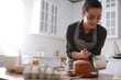 © New Africa - Young woman decorating traditional Easter cake with glaze in kitchen. Space for text