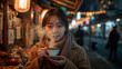 © bephoto - 夜の屋台前で日本人女性が湯気と吐息を重ね温かさを味わう