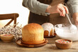 © New Africa - Woman putting glaze on Easter cake at wooden table, closeup