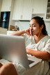 © Marko Geber - Young woman working on laptop at home kitchen