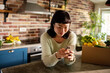 © Davor - Woman using smartphone in home kitchen with fresh grocery delivery