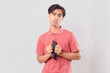 © Muhammad Alimaki - poor young adult Asian man holding empty wallet with confused expression