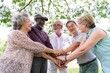 © Rawpixel.com - Group of diverse senior friends smiling and stacking hands outdoors. Elderly friends enjoying time together. Friendship. Diverse senior men and women putting their hands together in the park.