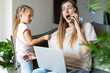 © Алина Бузунова - Stressed woman working from home while talking on phone and caring for daughter