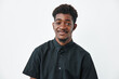 © SHOTPRIME STUDIO - Young black man with dark skin and curly hair wearing black shirt smiling and looking at camera on white background. Portrait of confident african ethnicity male with casual style.