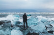 © Cavan Images - Woman stands on block of ice at Diamond Beach, Iceland