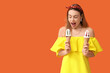© Pixel-Shot - Surprised young woman holding ice creams in waffle cone on orange background
