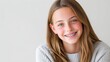 © ISVO - Smiling teenage girl with braces wearing a cozy gray sweater poses against a light neutral background, showcasing her cheerful expression and youthful appearance