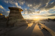© Travel 'n' Lifestyle - View of surreal rock formations casting long shadows in the desert landscape as the sun bursts on the horizon under a dramatic sky, Farmington, New Mexico, United States.
