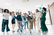 © deagreez - Group of diverse office coworkers celebrating a success together with confetti and champagne in bright workplace setting