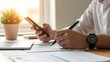 © Jignesh - Business professional reviewing documents at a desk with a smartphone nearby