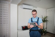 © Jelena - HVAC technician checking air conditioner using digital tablet