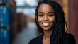 © Yuliia - Young African American woman with braided hair smiling confidently in urban setting. Professional portrait for business, lifestyle and diversity content.