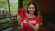© Krakenimages.com - Young woman volunteer holding red gift box with hands on building balcony; happiness generosity community.
