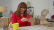 © Krakenimages.com - Senior woman in new home living room joyfully using smartphone surrounded by moving boxes showcasing a fresh start and connection