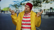 © Krakenimages.com - Young man with beard in yellow jacket and red striped shirt making peace sign on urban street background suggesting vibrant city life.