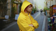 © Krakenimages.com - Confident man in yellow raincoat with crossed arms on a city street with blurred background, displaying a serious expression while outdoors in an urban environment.