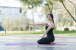 © Kritdanai - Serene Pose: A woman in athletic attire practices yoga on a mat in a park, embracing the tranquility of the outdoor environment.