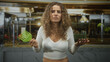 © Krakenimages.com - Woman with curly hair holding green comb, palms raised in restaurant kitchen, furrowed brow and puzzled expression; frustration hair care.