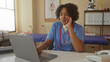 © Krakenimages.com - African american woman doctor with hand on chin looking at laptop in clinic building; thinking concern.
