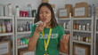© Krakenimages.com - Woman talking on phone in donation center wearing green volunteer t-shirt surrounded by shelves and boxes indoors