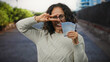 © Krakenimages.com - Woman smiling outdoors in a city street in malaysia holding ringgit banknotes doing a peace gesture in front of her eye.