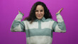 © Krakenimages.com - Hispanic woman smiling with glasses against a pink background, wearing a striped sweater, expresses playful cheerfulness and excitement.