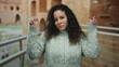 © Krakenimages.com - Woman gesturing playfully at roman ruins background in outdoor setting with ancient architecture showcasing a young hispanic female in casual attire.