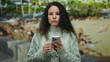 © Krakenimages.com - Woman in sweater using smartphone near beach with sea background depicts hispanic woman standing outdoors.