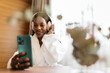 © ADDICTIVE STOCK - Woman relaxing in hotel room with headphones and smartphone