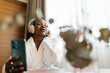 © ADDICTIVE STOCK - Woman relaxing in hotel room with headphones and smartphone
