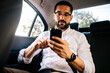 © kleberpicui - Business man using smartphone while commuting in car