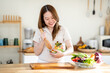 © Kittipong - An Asian woman is making a salad in the kitchen. The concept is related to healthy eating and dieting.