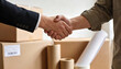 © Art_spiral - Close up handshake for moving and relocation service with packed cardboard boxes packing supplies and customer agreement home office transfer storage logistics concept