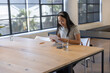 © wavebreak3 - Asian woman reviewing papers on table with smartphone in office meeting room, copy space