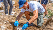 © Konstantin divelook - Dedicated volunteers uncover ancient artifacts during an archaeological dig in a sunlit valley surrounded by rolling hills
