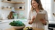 © MIKHAIL - Woman standing in a modern kitchen using a digital tablet to view augmented reality nutritional information and tracking dietary intake of healthy vegetables
