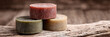 © Strother - A luxurious stack of three cylindrical artisan soap bars resting on a deeply textured, weathered wooden surface, captured with evocative studio light.