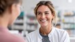© Yevheniiya - A pharmacist smiles warmly at a customer while discussing medication in a modern pharmacy setting.