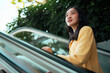 © Parichat - Asian woman moving up escalator looking optimistic