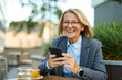 © Lumos sp - Portrait of a mid aged mature businesswoman using a mobile phone smartphone in a restaurant or coffee shop